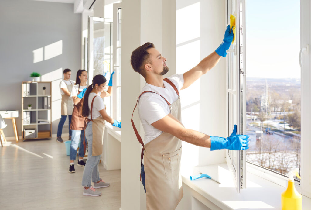 Male cleaner and group window washing, working, professional janitor service busy completing cleaning tasks at home, office. People employed to take care of room, small company maintaining apartment